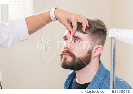 Medicine, health, ophthalmology concept - Ophthalmologist examines patient's eyes. Medicine, health, ophthalmology concept - Ophthalmologist examines patient's eyes. 63838978