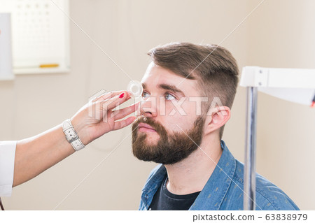 Medicine, health, ophthalmology concept - Ophthalmologist examines patient's eyes. Medicine, health, ophthalmology concept - Ophthalmologist examines patient's eyes. 63838979