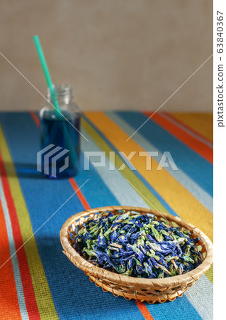 dried blue tea flowers in a wicker basket on a striped tablecloth, tea to go, selective focus dried blue tea flowers in a wicker basket on a striped tablecloth, tea to go, selective focus 63840367
