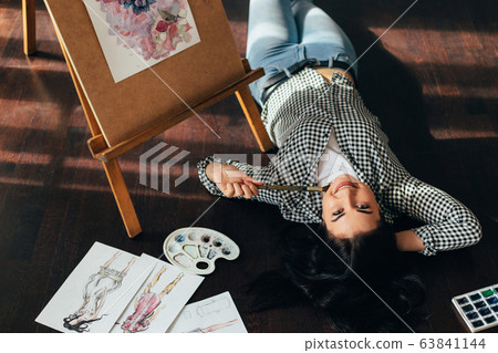 woman dreaming laying on the floor with sketches 63841144