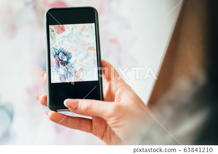 woman taking picture of floral watercolor painting 63841210