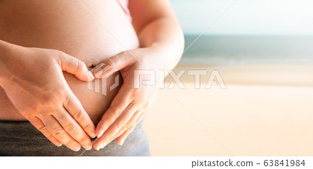Pregnant woman feeling happy at the beach. Pregnant woman feeling happy at the beach. 63841984