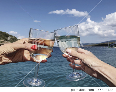 toasting wine glasses against sea and sky in toasting wine glasses against sea and sky in 63842488