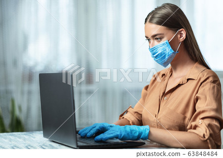 Girl wearing face mask and working on laptop, side view 63848484