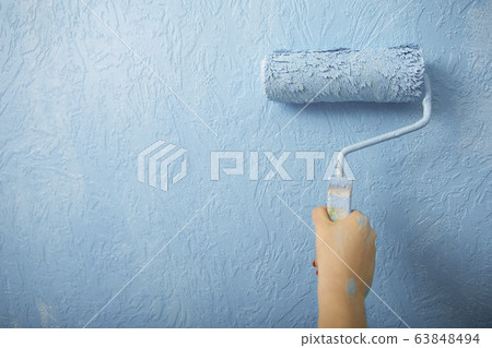 Idea for home interior. Girl paints wall in blue Idea for home interior. Girl paints wall in blue 63848494