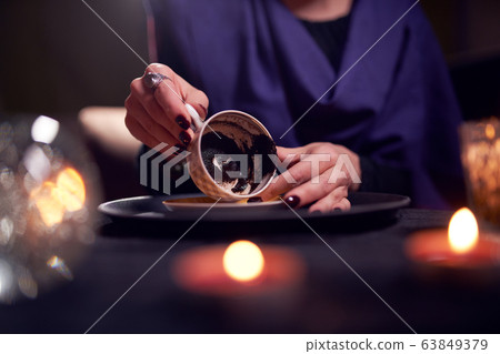 Close-up of fortuneteller's hands divining on coffee grounds at table with predictive ball 63849379