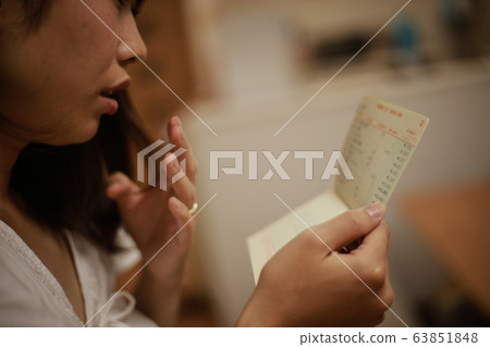 A woman worried about looking at a bankbook 63851848