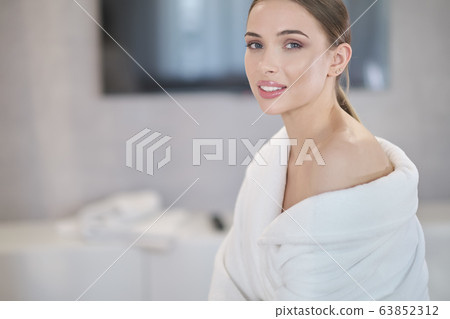 Beautiful young woman in bathrobe resting on bed Beautiful young woman in bathrobe resting on bed 63852312