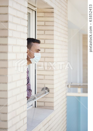 man wearing a surgical mask in the window 63852453