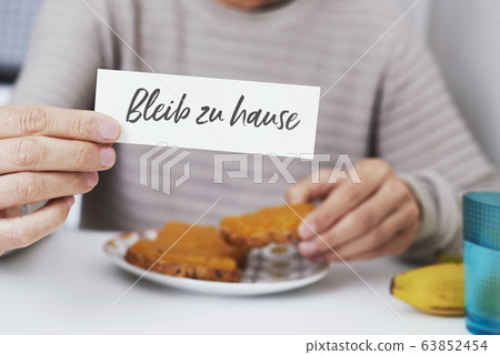 man showing the message stay at home in german man showing the message stay at home in german 63852454