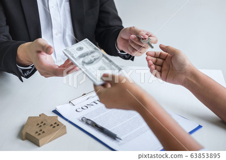 Estate agent giving house keys to client after 63853895
