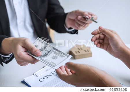 Estate agent giving house keys to client after 63853898