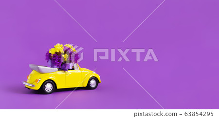 View of a colorful yellow convertible car with a bouquet of flowers on a pink background that leaves the blue cloud in the form of a heart. Concept holiday, delivery, art, background, transport. View of a colorful yellow convertible car with a bouquet of flowers on a pink background that leaves the blue cloud in the form of a heart. Concept holiday, delivery, art, background, transport. 63854295