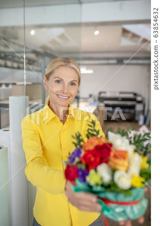 Blonde woman receiving flowers and feeling happy Blonde woman receiving flowers and feeling happy 63854632