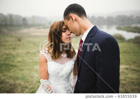 Romantic wedding moment, couple of newlyweds smiling portrait, bride and groom hugging 63855039