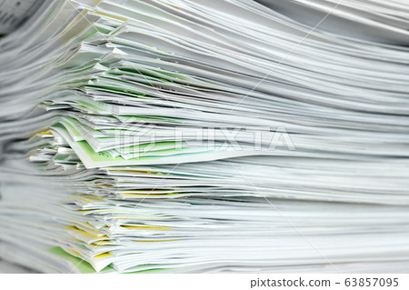 A stack of office papers on a table. 63857095