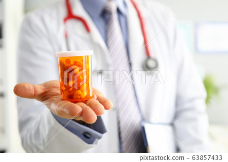 Male medicine doctor hand holding and offering to patient jar of pills 63857433