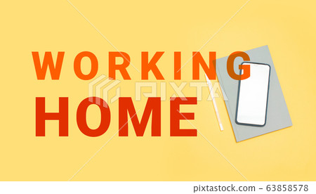 Work home. Top view of a gray notebook, smartphone and pen with copy space on a yellow background. Workplace, freelance. Stay at home 63858578