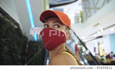 Woman travel caucasian visitor at a supermarket with wearing protective medical mask. Girl tourist customer a grocery store with protect respirator. Woman travel caucasian visitor at a supermarket with wearing protective medical mask. Girl tourist customer a grocery store with protect respirator. 63859812