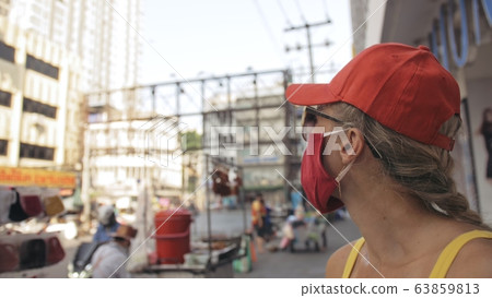 Woman travel caucasian visitor at a supermarket with wearing protective medical mask. Girl tourist customer a grocery store with protect respirator. Woman travel caucasian visitor at a supermarket with wearing protective medical mask. Girl tourist customer a grocery store with protect respirator. 63859813