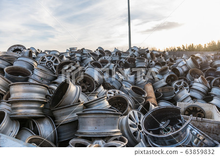 Mountain of car rims piled up in a junkyard. 63859832