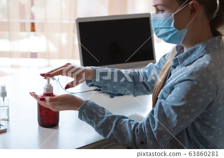 Young woman in face mask disinfecting gadgets surfaces on her workplace Young woman in face mask disinfecting gadgets surfaces on her workplace 63860281