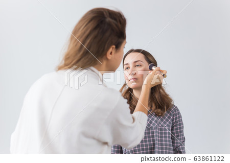 Beauty and cosmetics concept - Makeup artist doing professional make up of young woman Beauty and cosmetics concept - Makeup artist doing professional make up of young woman 63861122