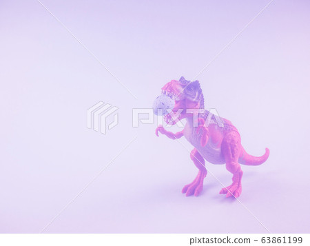 Angry dinosaur toy with easter egg in mouth. Toned 63861199