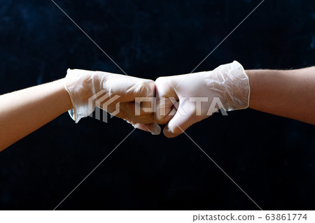 Hands of friends in medical gloves greeting each other with fist bump. Hands of friends in medical gloves greeting each other with fist bump. 63861774