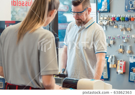 Woman customer talking to keymaker or locksmith Woman customer talking to keymaker or locksmith 63862363