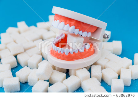 A peace of sugar in the fake jaw with a lot of holes in teeth isolated. 63862976