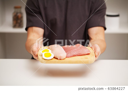 Athletic man holding a board with meat for proper nutrition of the athlete 63864227