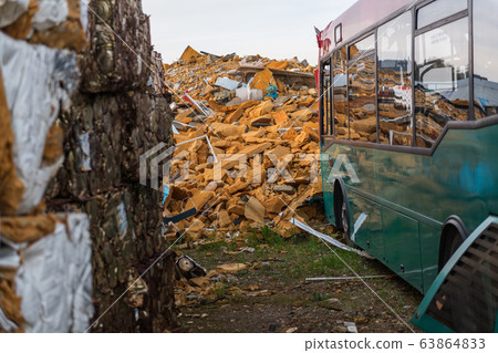 Abandoned city bus in a junkyard close to a orange insulating foam mountain Abandoned city bus in a junkyard close to a orange insulating foam mountain 63864833