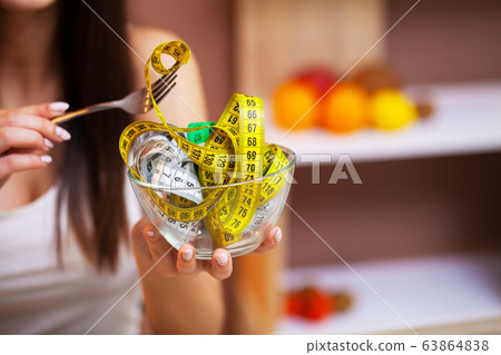 Girl holding a transparent plate full of measuring tape Girl holding a transparent plate full of measuring tape 63864838