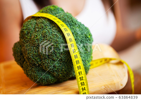 Closeup of woman holding broccoli with string tape to measure 63864839