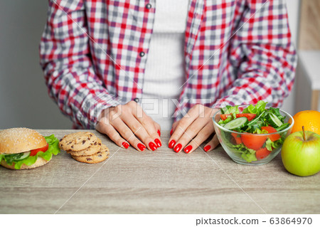 Woman makes a choice between harmful and healthy foods Woman makes a choice between harmful and healthy foods 63864970
