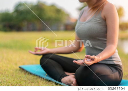 Asian woman meditating and sit in the lotus pose Asian woman meditating and sit in the lotus pose 63868504