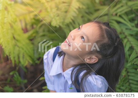 Happy Asian student sitting in green garden Happy Asian student sitting in green garden 63878175