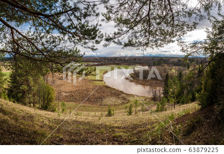 View at the river valley covered with forest and solitary trees. Sky visible through tree branches View at the river valley covered with forest and solitary trees. Sky visible through tree branches 63879225