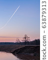 Morning sky with airplane track above the river 63879313