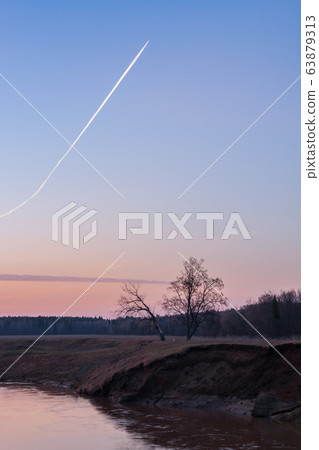 Morning sky with airplane track above the river 63879313