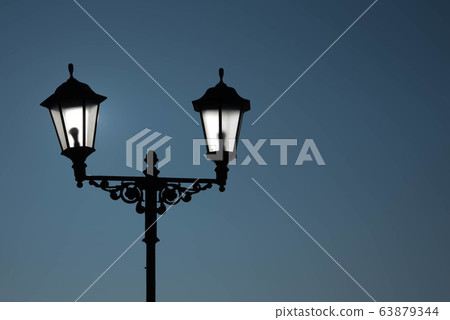 Urban landscape. Street lamp with a lamp in a classic style against a purple sky. Beautiful postcard. 63879344
