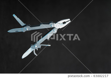 Multitool is a multi-functional tool on a black Multitool is a multi-functional tool on a black 63882217