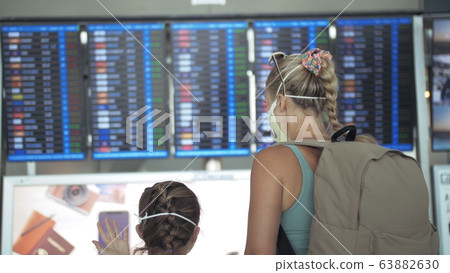 Woman and child baby tourist caucasian at airport with wearing protective medical mask. Family in quarantine isolation. Coronavirus covid-19. Woman and child baby tourist caucasian at airport with wearing protective medical mask. Family in quarantine isolation. Coronavirus covid-19. 63882630