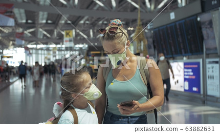 Woman and child baby tourist caucasian at airport with wearing protective medical mask. Family in quarantine isolation. Coronavirus covid-19. Woman and child baby tourist caucasian at airport with wearing protective medical mask. Family in quarantine isolation. Coronavirus covid-19. 63882631