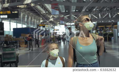 Woman and child baby tourist caucasian at airport with wearing protective medical mask. Family in quarantine isolation. Coronavirus covid-19. Woman and child baby tourist caucasian at airport with wearing protective medical mask. Family in quarantine isolation. Coronavirus covid-19. 63882632