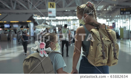 Woman and child baby tourist caucasian at airport with wearing protective medical mask. Family in quarantine isolation. Coronavirus covid-19. Woman and child baby tourist caucasian at airport with wearing protective medical mask. Family in quarantine isolation. Coronavirus covid-19. 63882634