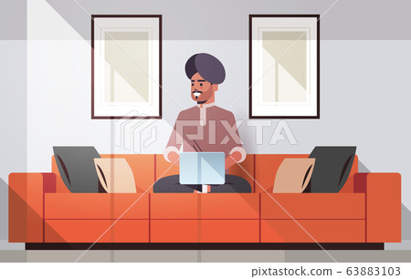 indian man in turban sitting on couch using laptop guy working from home freelance concept modern living room interior horizontal full length indian man in turban sitting on couch using laptop guy working from home freelance concept modern living room interior horizontal full length 63883103