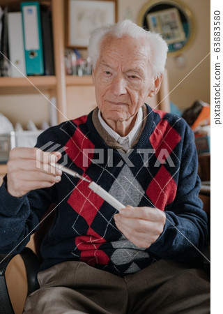Senior Elderly Man Holding thermometer in Hands. 63883580