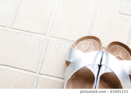 Take silver and brown slippers diagonally on the tile 63885133
